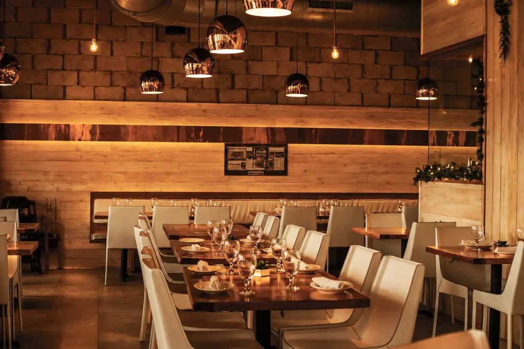 The dining room at Kareem's Lebanese Kitchen, featuring warm ambient lighting, wood-accented interiors, an open kitchen, and an inviting upscale atmosphere.