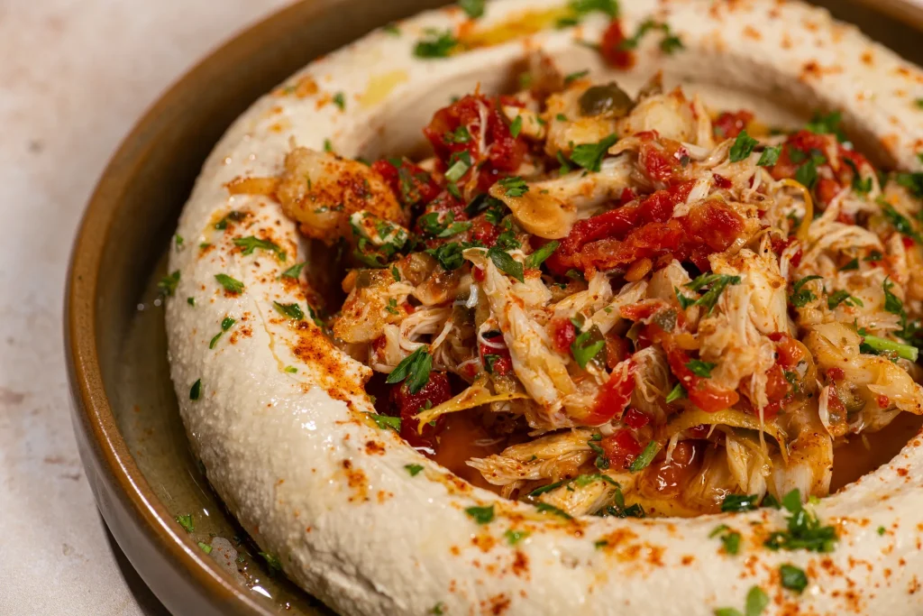 Hummus ring filled with lump crab, sun-dried tomatoes and parsley, dusted with paprika