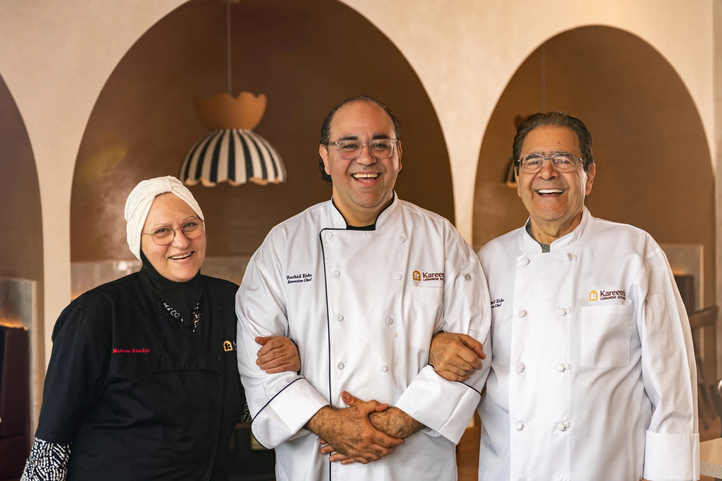 Khadija, Rachid and Jamil Eido, smiling arm in arm in the dining room
