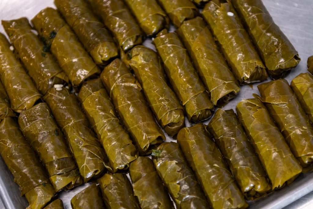 Rows of hand-rolled stuffed grape leaves lined up on a metal tray
